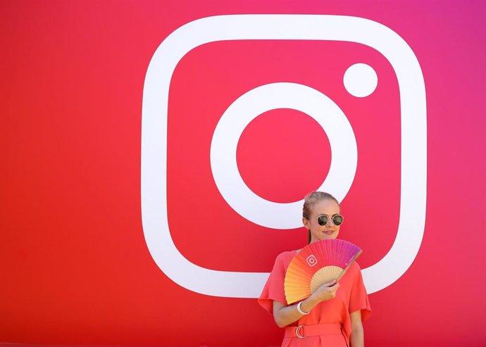 Joven posando delante del logotipo de Instagram