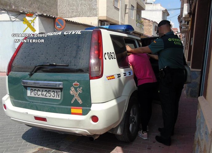 Un agente de Guardia Civil introduce a la detenida en el coche de la Benemérita