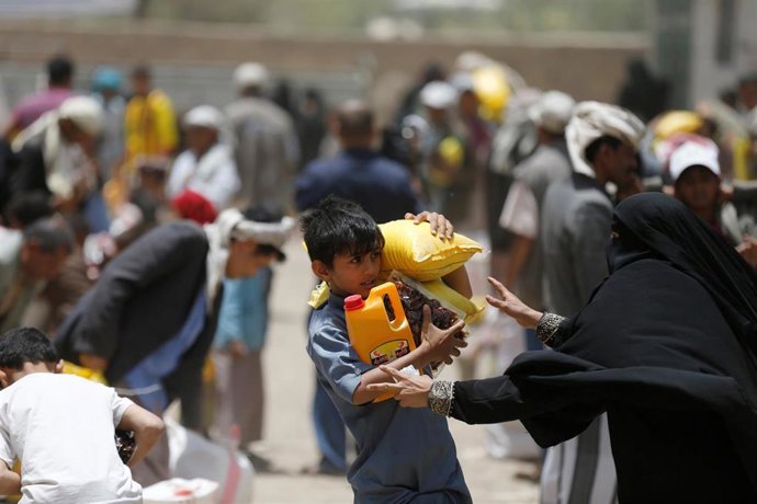 Un niño carga comida y bebida recibida de una organización benéfica local en Sanaa, Yemen. 5 junio de 2016 REUTERS/Khaled Abdullah