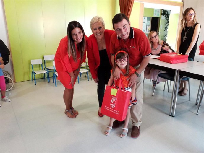 El alcalde de Hospital de Órbigo, Enrique Busto, junto a la presidenta del PSOE provincial, Montserrat Álvarez, y la procuradora socialista Nuria Rubio, entregan material escolar a un niño.