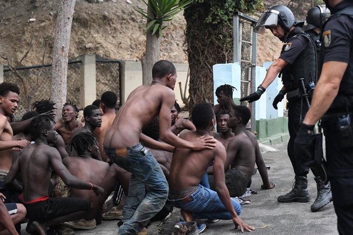 Imagen de inmigrantes y efectivos policiales ante el salto masivo a la valla de Ceuta el 30 de agosto 