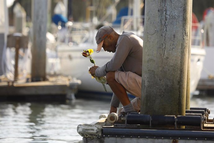 Un hombre pone flores en honor a las víctimas de la tragedia del Conception. 