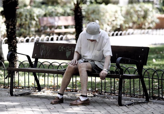 Un pensionista descansa en un banco de un parque de Madrid.