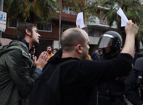 People hold up ballot sheets to riot police outside a polling station for the ba