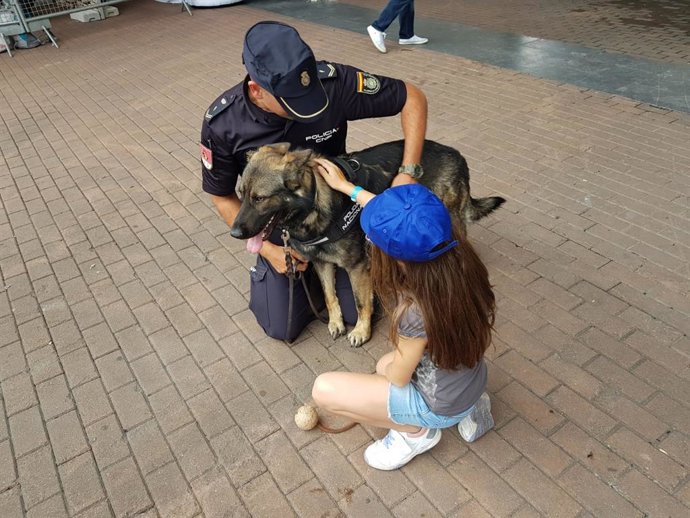 Un policía enseña un perro de la Unidad Canina a una de las niñas asistentes al stand de la Vuelta en Bilbao