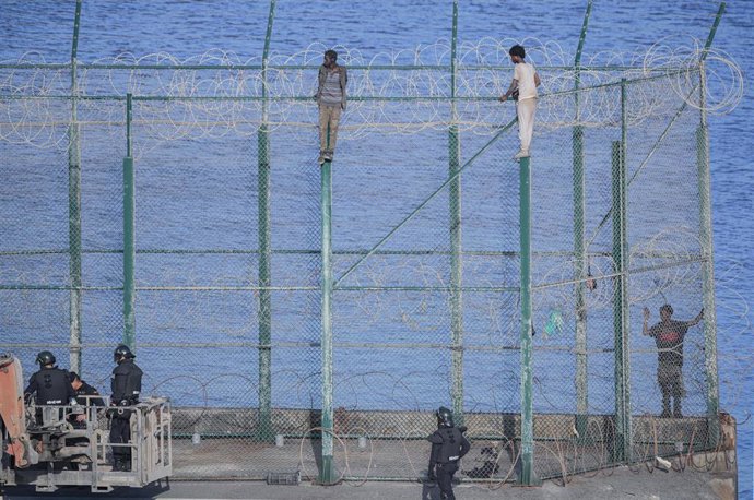 En la imagen, tres de un total de 153 migrantes, entran en Ceuta saltando su doble valla en la primera incursión en grupo en un año.