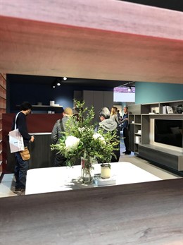 Exposición de un salón con la TV vista a través de una estantería, Feria Mueble