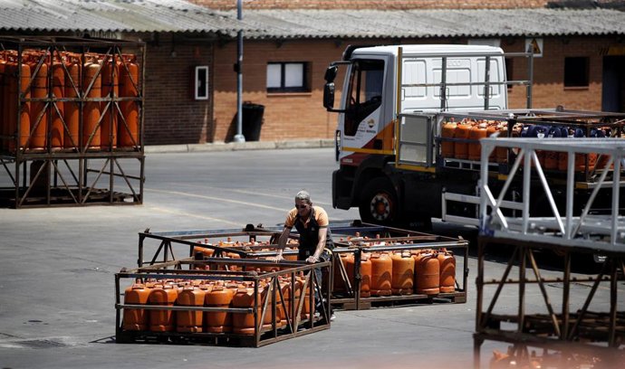 Un hombre apila bombonas de butano en un almacén.
