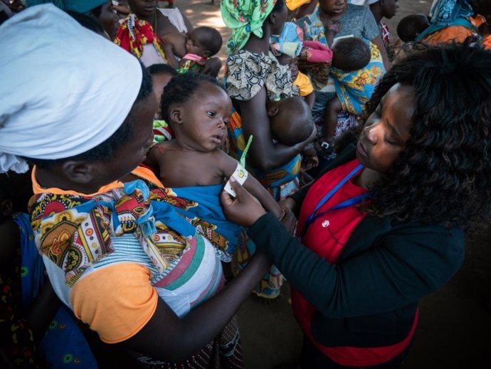 Una trabajadora de Save the Children pasa revisión médica a niño con su madre