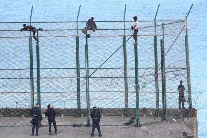 En la imagen, tres migrantes entran en Ceuta el 30 de agosto saltando su doble valla en la primera incursión en grupo en un año