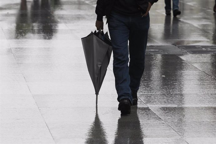 Una persona camina portando un paraguas.