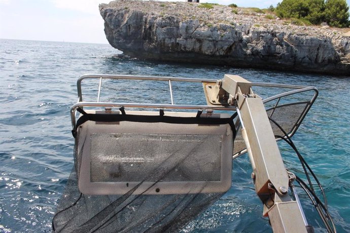 Una barca realitza tasques de neteja en el litoral de Balears.