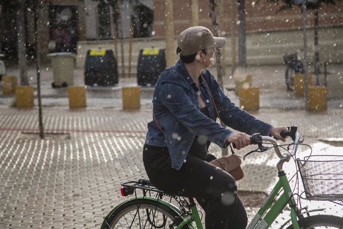 Ciclista soprendida por una tormenta en la Alameda de Hércules. Sevilla.
