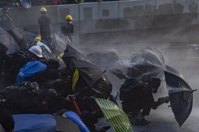 Manifestantes hongkoneses frente a los cañones de agua de la Policía.