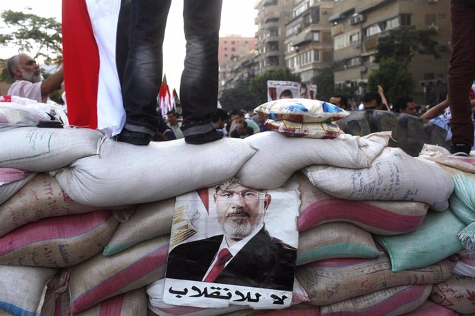 Un afiche con la imagen del depuesto presidente egipcio Mohamed Mursi es mostrado en una barrera hecha por miembros de los Hermanos Musulmanes y seguidores de Mursi para proteger el área donde acampan en la plaza Rab'a al- Adawiya, en el primer día del 