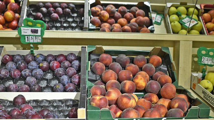 Variedad de frutas: caja de ciruelas, caja de nectarinas y caja de manzanas en un mercado de Madrid.