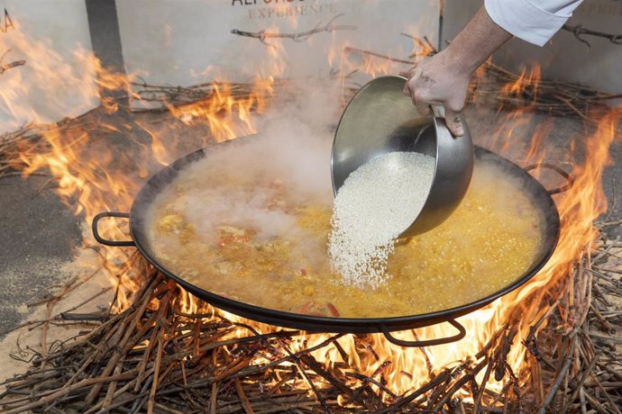 Un cocinero echa el arroz en una paella