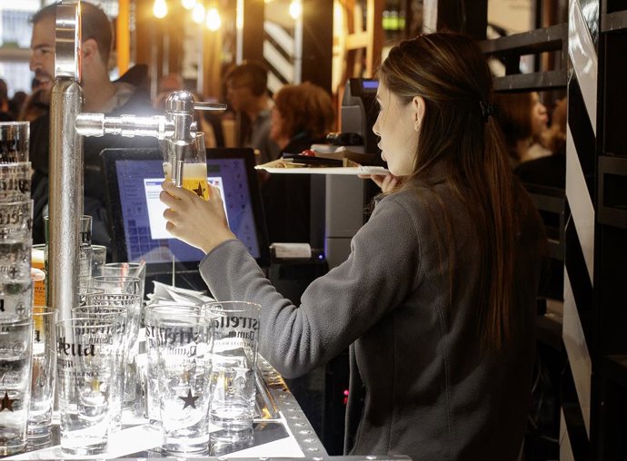Una cambrera serveix una cervesa en un bar