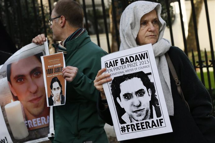 Manifestantes con carteles con la imagen del bloguero Raif Badaui frente a la Embajada de Arabia Saudí en Londres, Reino Unido