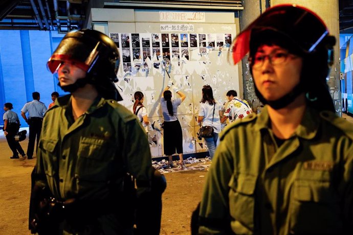 Policías antidisturbios frente a un grupo de partidarios de China que retira los mensajes de los 'Muros de Lennon'