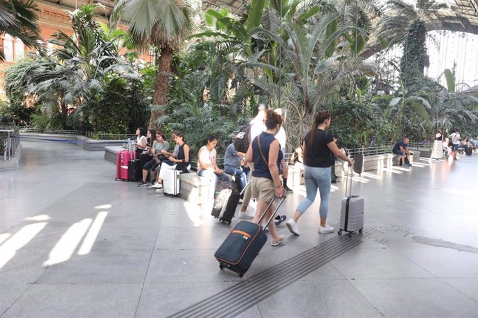 Pasajeros en la estación de tren Puerta de Atocha de Madrid esperan con sus maletas en el Jardín Invernadero de la estación durante la primera de las cuatro jornadas de paros parciales de Renfe a los que el sindicato CGT ha convocado a los trabajadores 