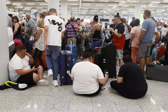 Turistes esperant davant els mostradors de Thomas Cook a l'aeroport de Palma de Mallorca. 