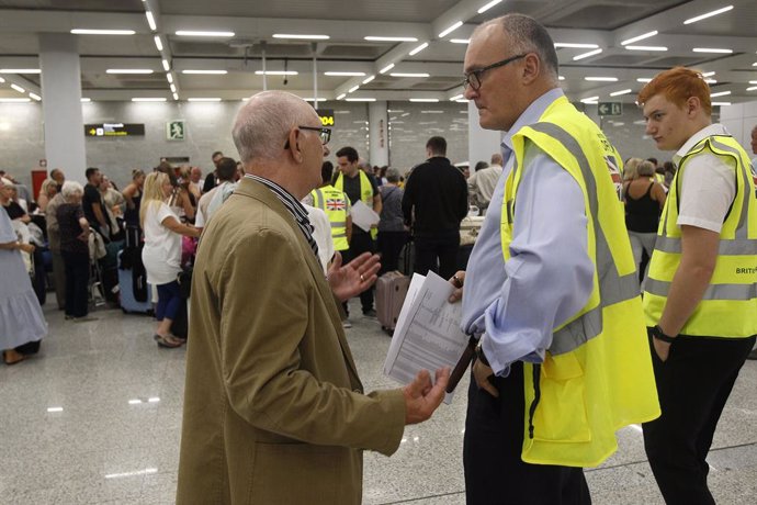 Un turista parla amb personal de seguretat a l'aeroport de Palma de Mallorca després de la fallida de Thomas Cook.   