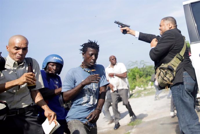 El senador haitiano Jean Marie Ralph Fethiere dispara con su pistola para dispersar a manifestantes que intentaban entrar en su vehículo