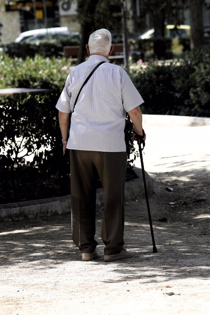 Un pensionista pasea con una garrota en una calle de Madrid.