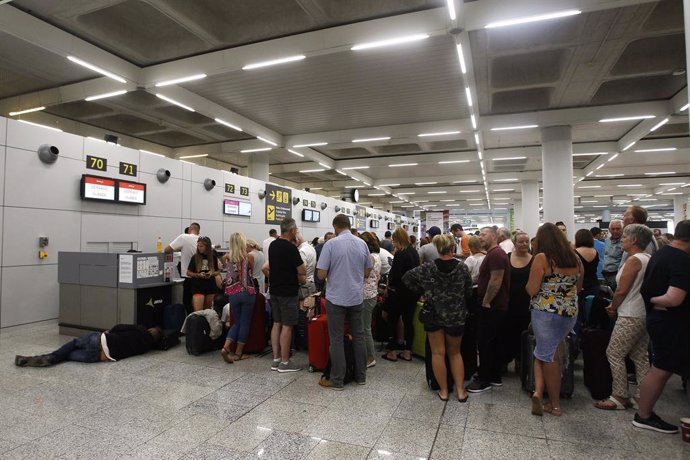 Turistes fent cola en els taulells de la companyia Thomas Cook a l'aeroport de Palma de Mallorca.    