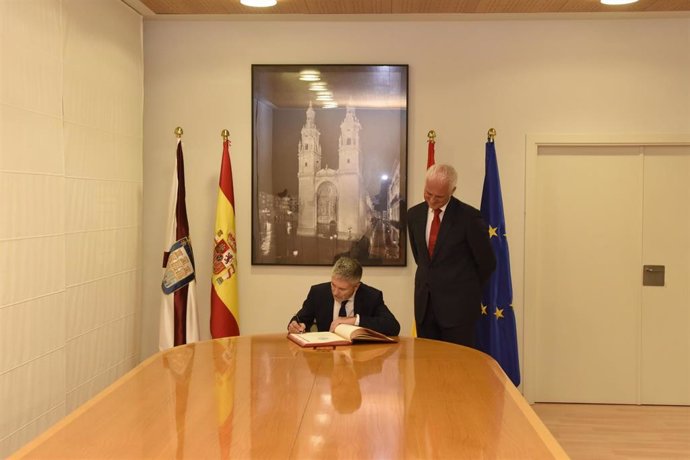 El ministro de Interior, Fernando Grande-Marlaska, firma en el libro oficial del Ayuntamiento ante el alcalde, Pablo Hermoso de Mendoza, durante su visita a Logroño por la celebración del Día de la Policía