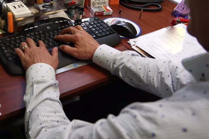 Las manos de un hombre, escriben en el teclado del ordenador, en la oficina.