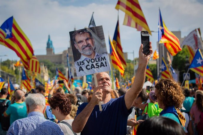 Un hombre sujeta un cartel con la foto del preso del Procés y Presidente de mnium Cultural, Joredi Cuixart, en la que se lee `Us Volem,a casa(os queremos en casa)  junto con banderas de la  estelada (bandera independentista catalana) durante la manifest