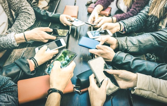 Jóvenes compartiendo contenido en redes sociales con teléfonos inteligentes móviles