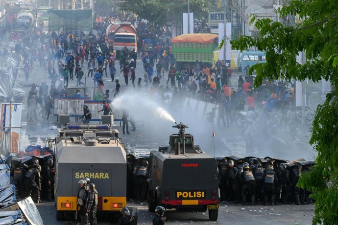 Agentes de Policía cargando con gases lacrimógenos contra manifestantes en Makassar