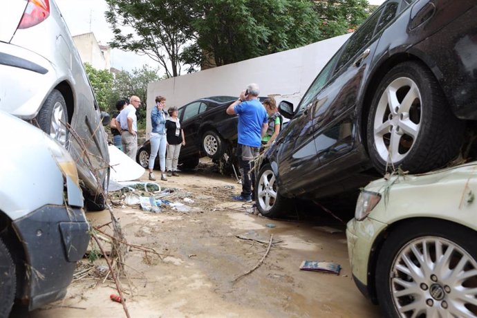 Algunas personas observan coches gravemente dañados por las inundaciones en Tafalla (Navarra).