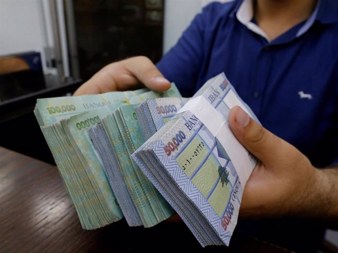Un trabajador de una casa de cambio en Beirut muestra varios fajos de libras libanesas