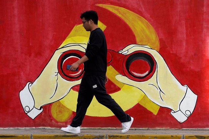 Un hombre camina frente a un mural  sobre el Partido Comunista de China (PCCh) en Shangái