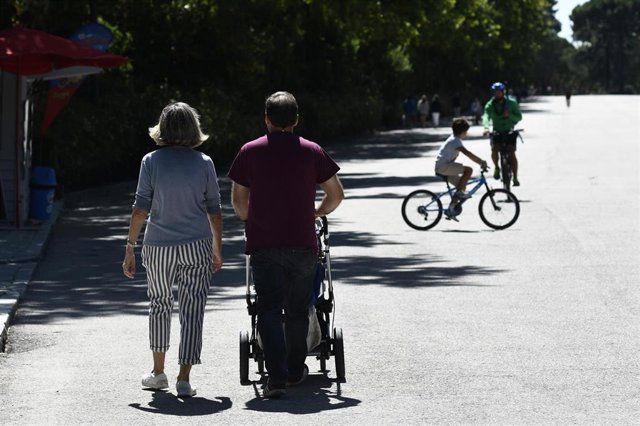 Una pareja con un carrito de bebé en un parque de Madrid.