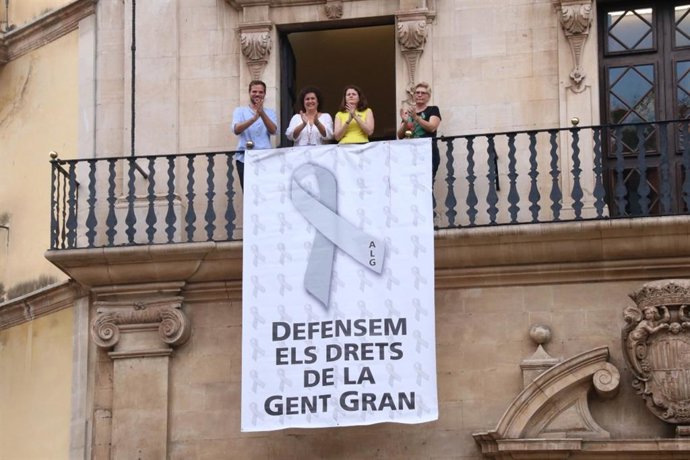 Miembros del equipo de Gobierno de Cort desplegan una pancarta en el balcón de Cort a favor de las personas mayores