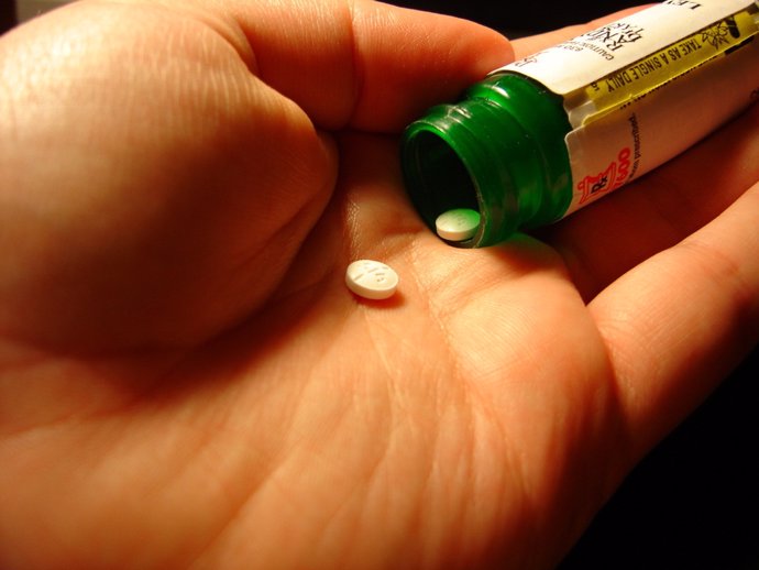 Par de pastillas saliendo de su envase en una mano para reflejar el consumo de medicamentos.