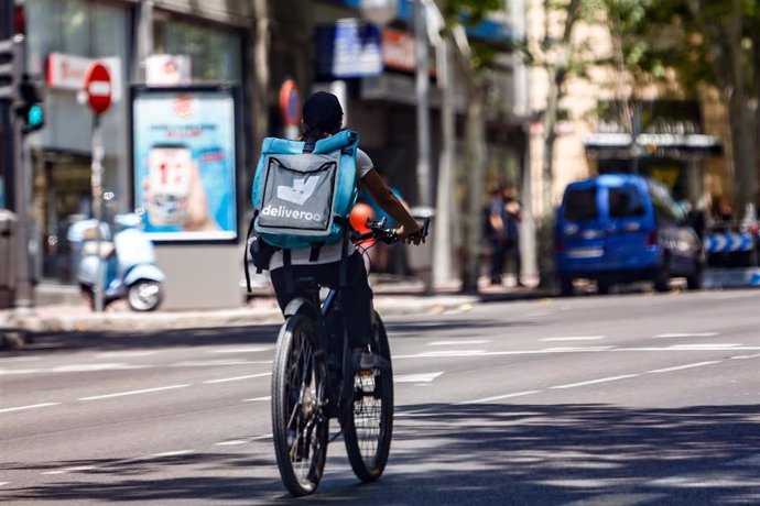 Un 'rider' de la compañía de comida a domicilio, Deliveroo, circula con su bicicleta por una calle de Madrid.