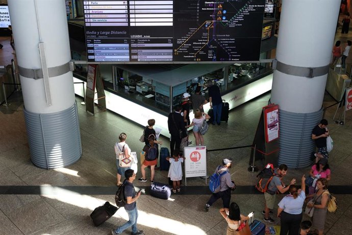 Varios viajeros hacen cola frente a un mostrador con el cartel de 'Renfe Cercanías Madrid' de la estación de trenes de Atocha durante la primera jornada de paros de Renfe de las cuatro que tienen programadas los sindicatos en verano.