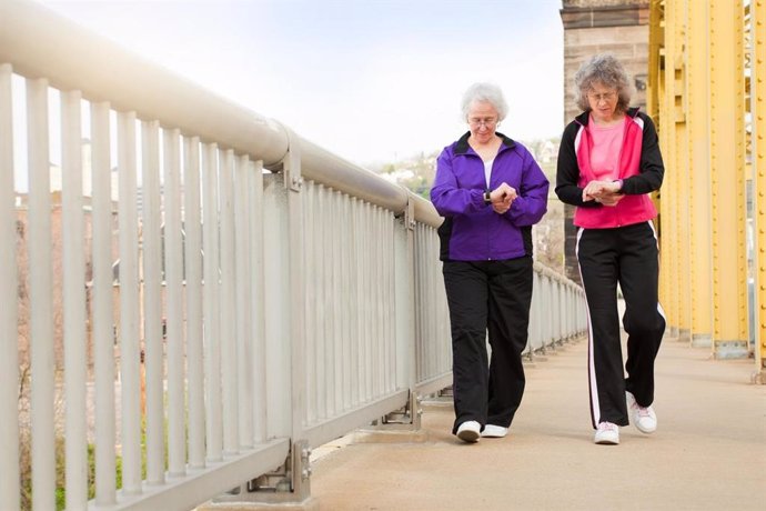 Mujeres mayores andando y consultando sus pulsers que cuentan los pasos