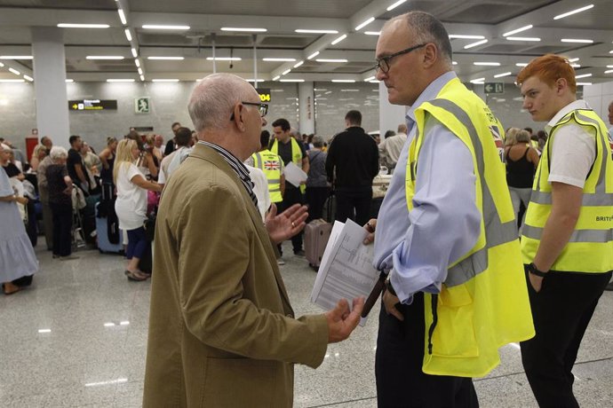 Un turista habla con dos guardas de seguridad mientras se forman largas colas en las ventanillas del aeropuerto de Palma de Mallorca (Baleares), horas después de que la compañía británica Thomas Cook anunciase su quiebra y de que varios de sus vuelos fu