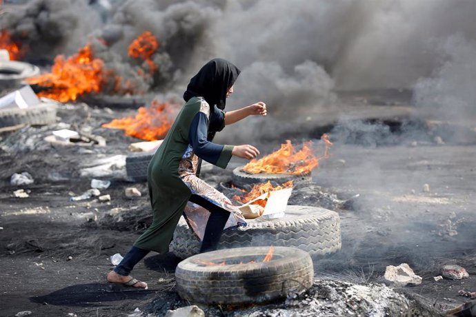 Una manifestante corre entre neumáticos ardiendo en Bagdad.