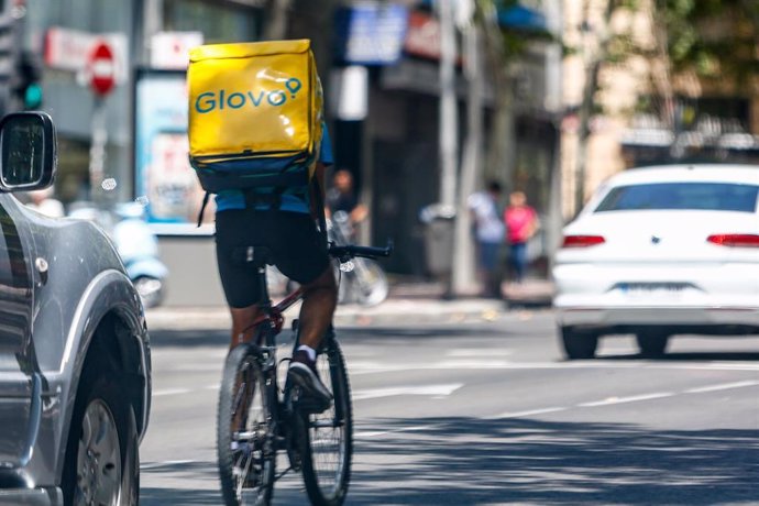 Un 'rider' de la compañía de comida a domicilio, Glovo, circula con su bicicleta por una calle de Madrid.