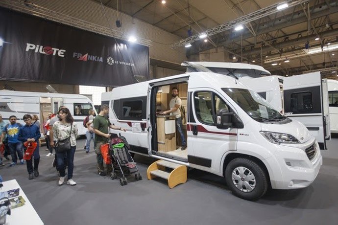 Visitantes miran un vehículo expuesto en el salón