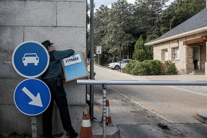 Una agente de la Guardia Civil coloca el cartel de cerrado en la valla de entrada de los coches al Valle de los Caídos. La basílica se cierra horas después del anuncio por parte del Gobierno de que los restos del dictador Francisco Franco saldrán del Va