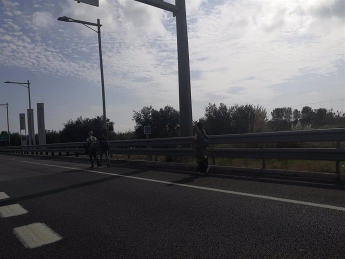 Personas que caminan por carretera hacia el Aeropuerto de Barcelona